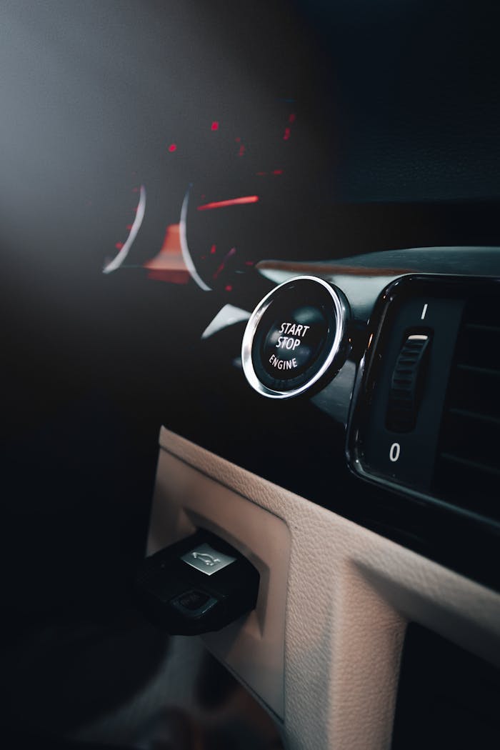services-04 Close-up of a car's dashboard featuring an illuminated start-stop button.